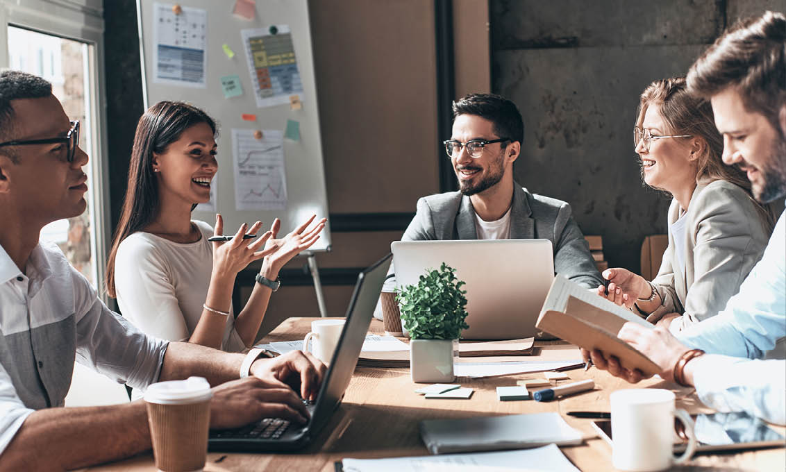 Working together. Group of young modern people in smart casual wear discussing business and smiling while sitting in the creative office