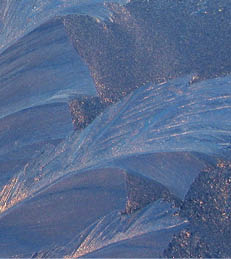 Beautiful ice pattern and sunlight close up on window glass early in the morning, natural winter background