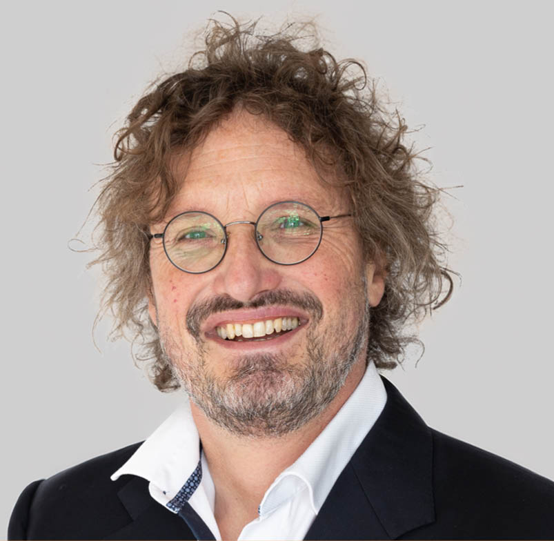 A man with a beard and glasses is smiling. Description generated by AI