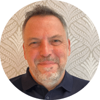 A man with a beard and mustache wearing a blue shirt. Description generated by AI