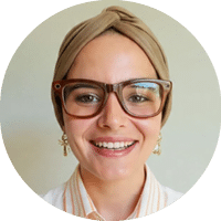A woman wearing glasses and a white shirt. Description generated by AI