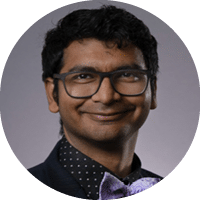 A man wearing a purple bow tie and glasses. Description generated by AI