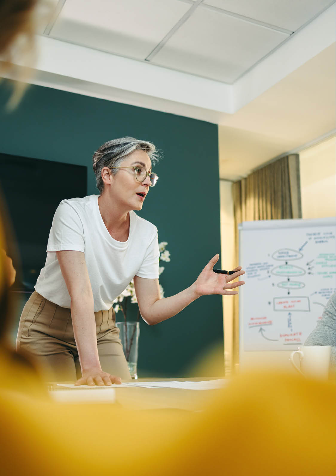 Experienced business professional leading a discussion with her team in a boardroom. Businesspeople sharing creative ideas during a meeting in a modern workplace.
