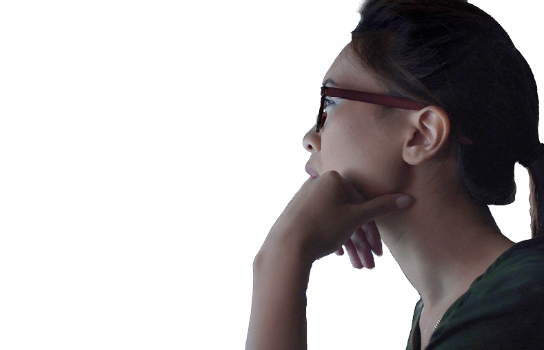 Stock photo of a young Asian woman looking at see through data whilst seated in a dark office