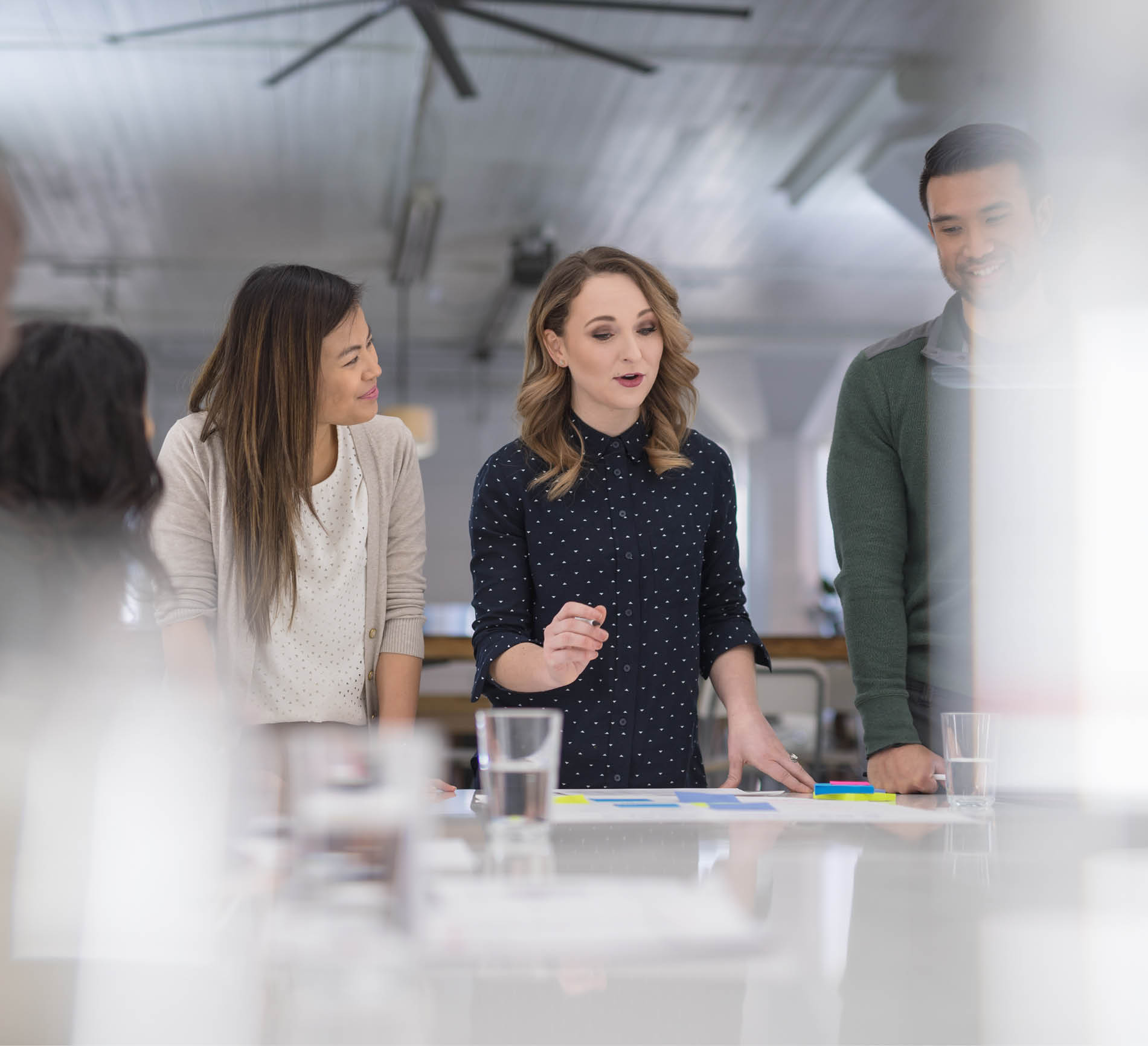 The CEO of a business startup gathers her multiethnic team around the conference table to finalize a product launch  She is signing paperwork and her coworkers are watching next to her 